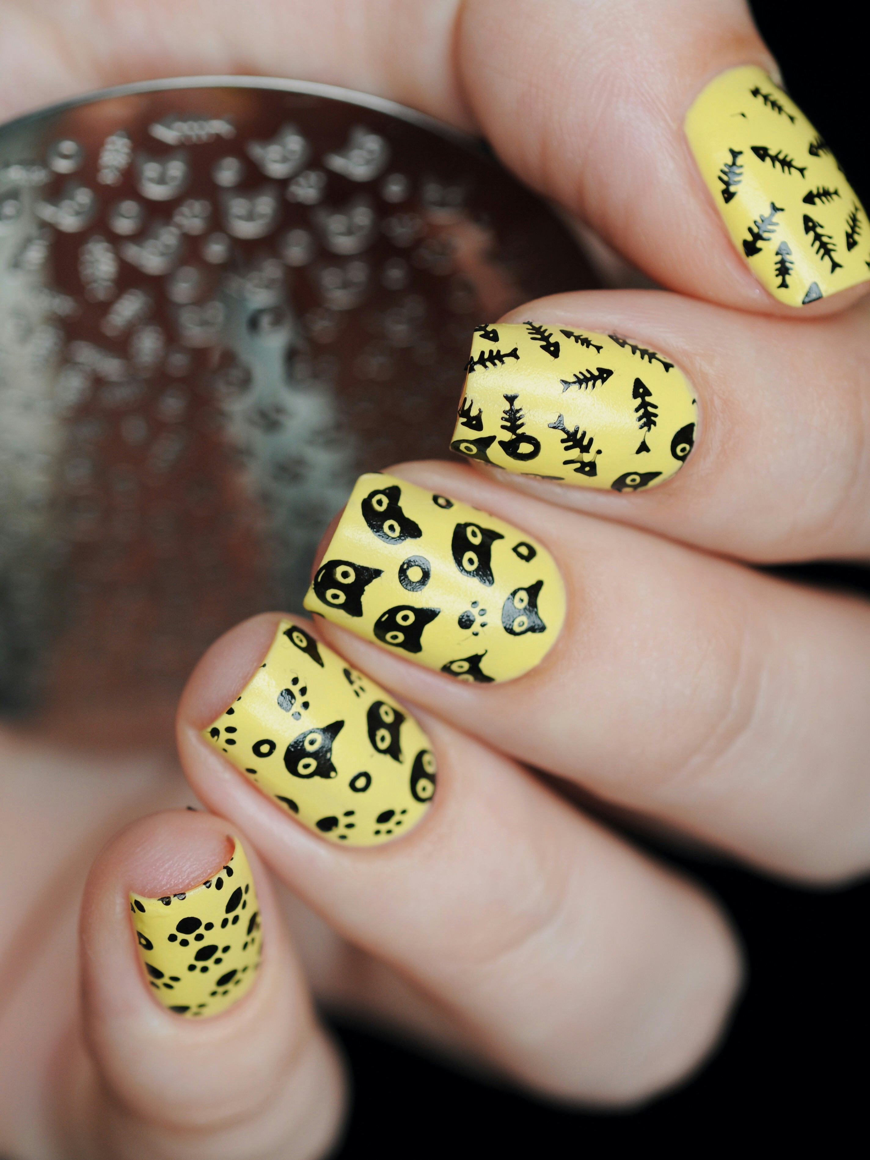 Cute yellow manicure with cats and a fish skeleton