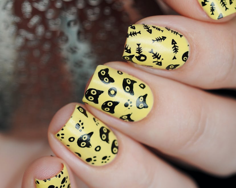 Cute yellow manicure with cats and a fish skeleton