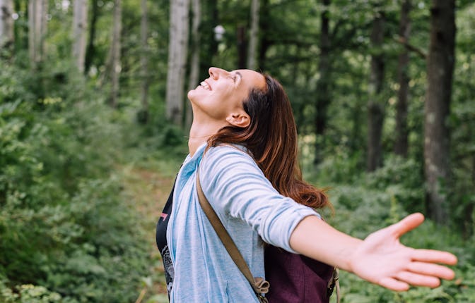 Woman forest bathing with arms outstretched enjoying nature adult caucasian woman in nature practisi...