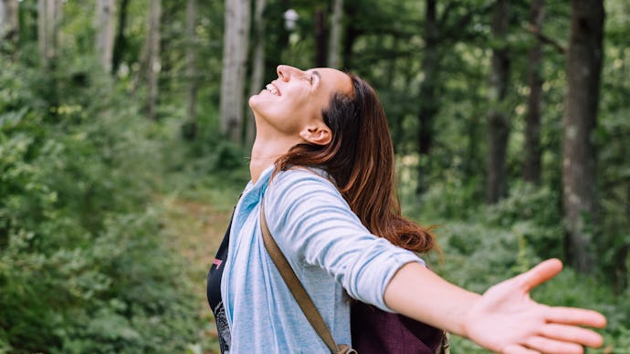 Woman forest bathing with arms outstretched enjoying nature adult caucasian woman in nature practisi...