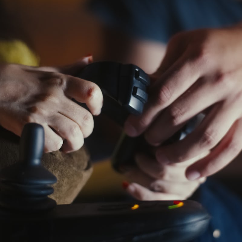 Unrecognizable man helping woman with disability in motorized wheelchair with gamepad and after she ...