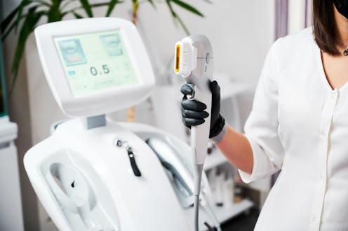 Close up of beautician hand in black glove holding ultrasound device for face lifting and skin tight...