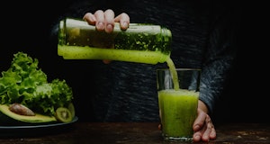 Woman making detox smoothie at home. Green food does the body good