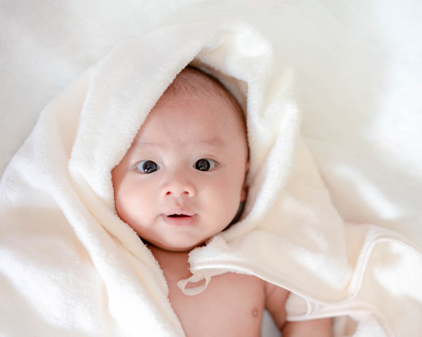 Adorable, Asian newborn laying with white blanket in article about boy names that begin with Y