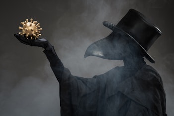 The plague doctor holds a golden model of the virus in his hand. 