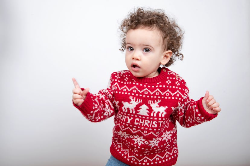 beautiful little baby boy with curly hair wearing red Christmas knitted sweater in article about boy...