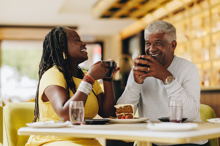Happy senior couple laughing cheerfully while having coffee together in a cafe. Carefree senior coup...