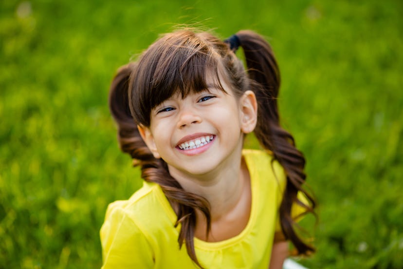 Happy little girl in yellow T-shirt laughs summer on the lawn. Xayah is a unique name that begins wi...