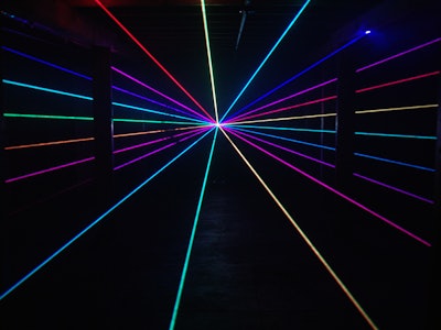 Thin rainbow laser beams shine past columns at nightclub background