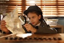 可爱的小侦探在办公室的桌子上用放大镜探索文件