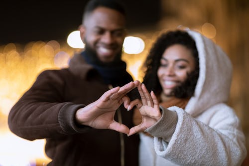couple forming a heart with their hands because they heard some cute Valentine's Day puns