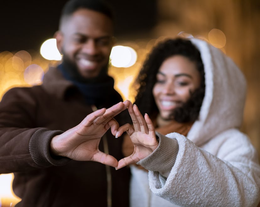 couple forming a heart with their hands because they heard some cute Valentine's Day puns