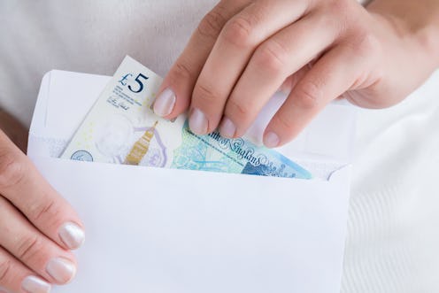 Money and white envelope in woman's hands. English pound.