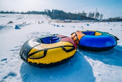 Two empty snow tubes at the top of a slope, in a story answering the question, can you go tubing whi...