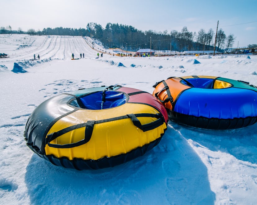 Two empty snow tubes at the top of a slope, in a story answering the question, can you go tubing whi...