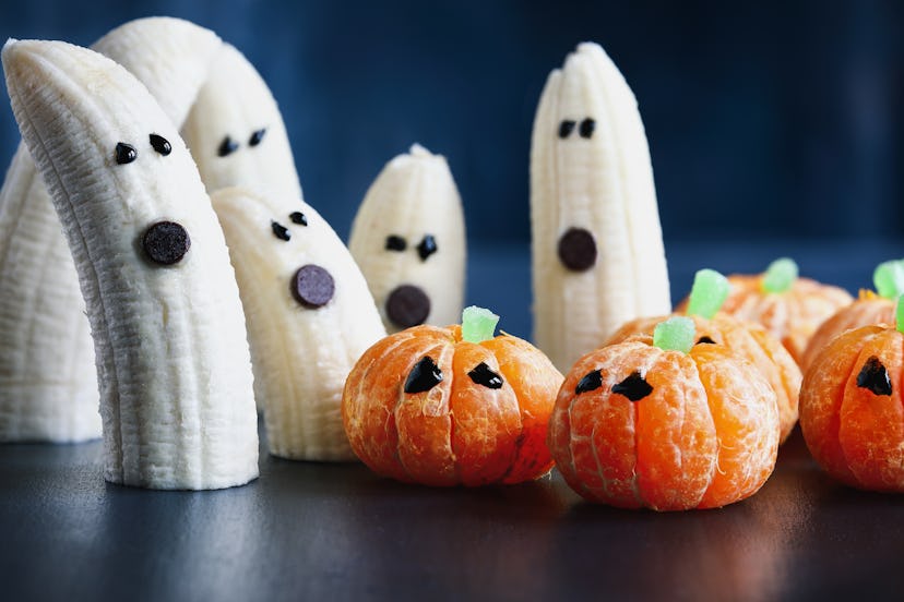 Halloween cute pumpkin orange fruit and scary banana ghosts monsters with chocolate faces. Healthy d...