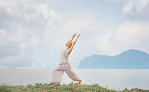 Senior woman doing yoga exercises with mountain and sky on the background