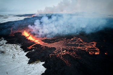 An aerial view taken with a drone shows lava and smoke spewing from a volcanic fissure during an eru...