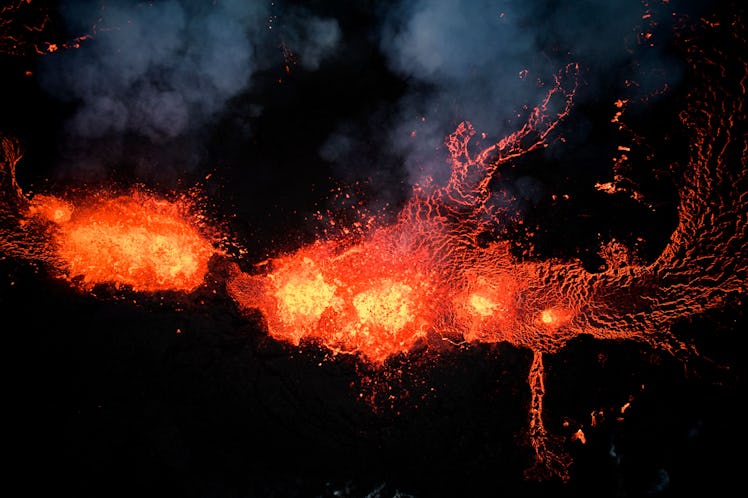 An aerial view taken with a drone shows lava and smoke spewing from a volcanic fissure during an eru...