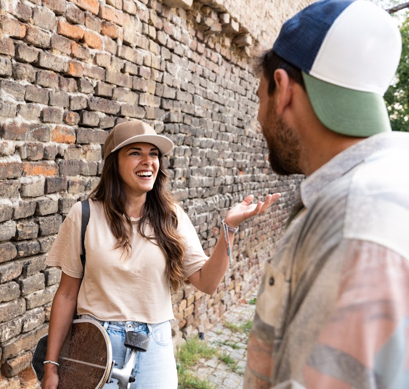 Portrait of young couple with skateboard and longboard having fun outdoors. Man and woman boyfriend ...
