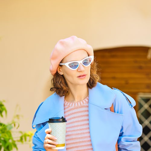 Stylish woman with cardboard glass of coffee in her hand in a hurry