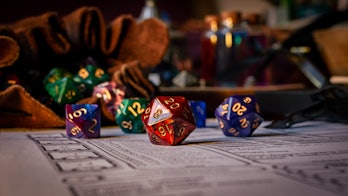 Close up of spilling out dice of different kinds from a dice bag on a character sheet.