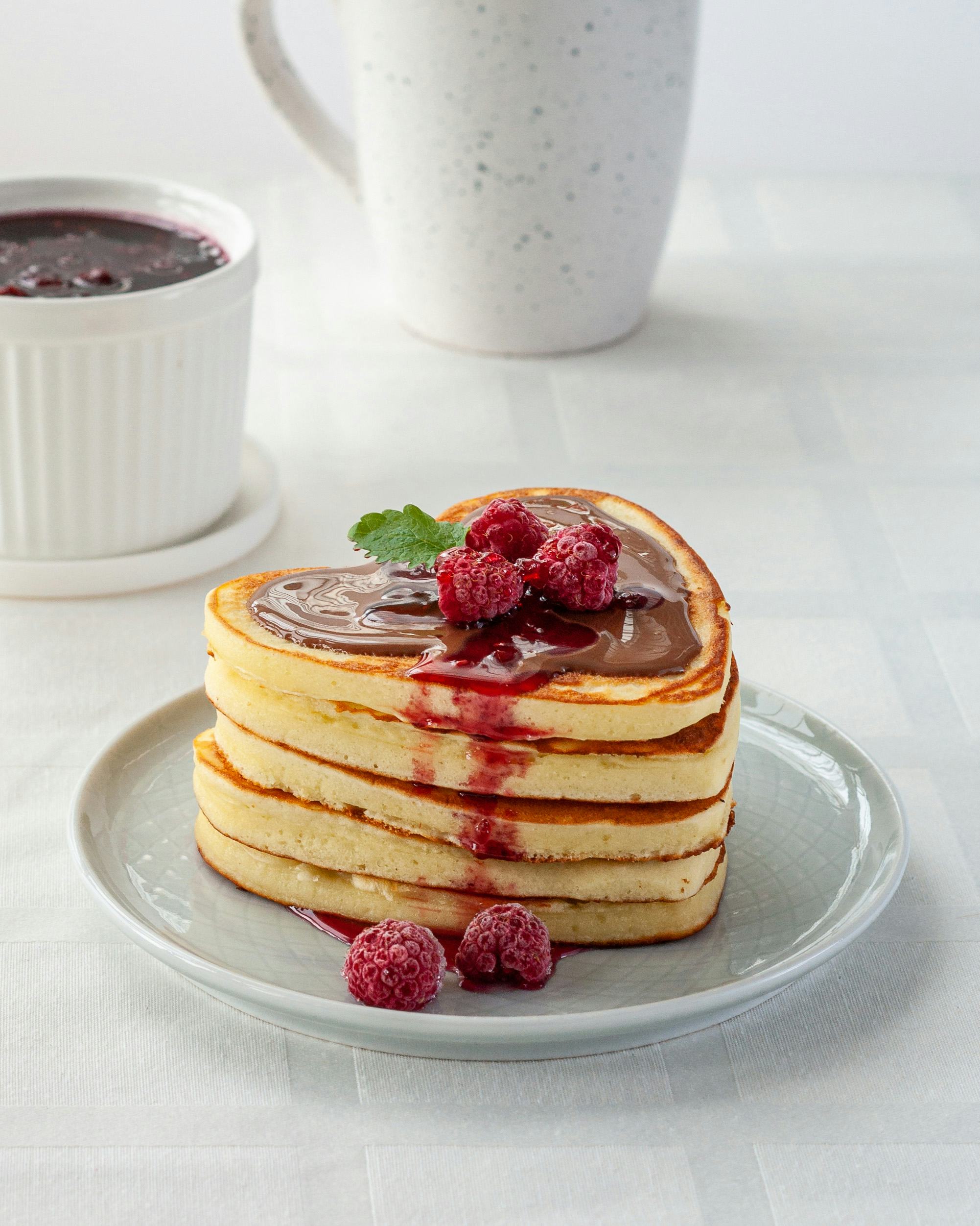Homemade heart shaped pancakes stack with chocolate and raspberries