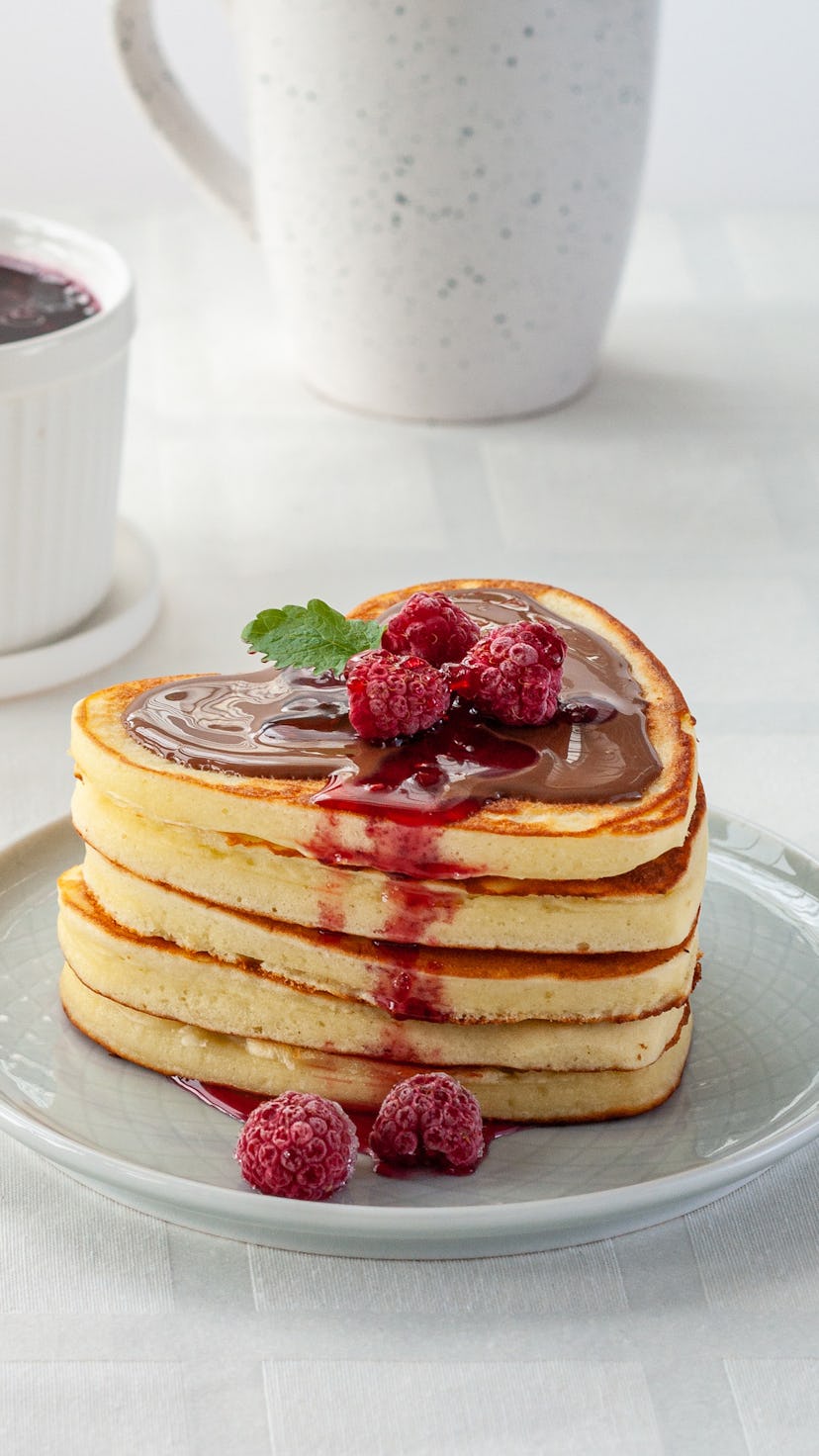 Homemade heart shaped pancakes stack with chocolate and raspberries