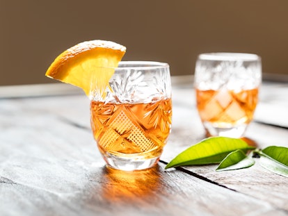 Two shots with tangerine liqueur on an old wooden table