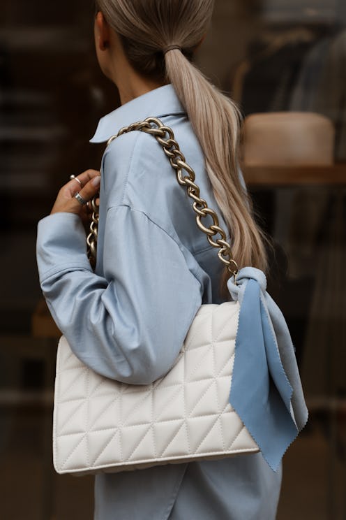 white bag with a blue scarf on the shoulders of a girl model close up, stylish summer fashion look i...