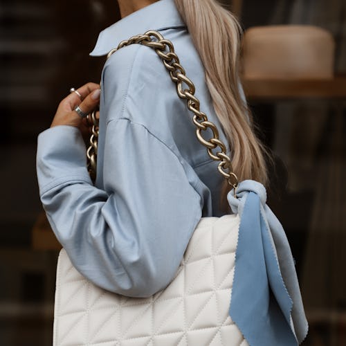 white bag with a blue scarf on the shoulders of a girl model close up, stylish summer fashion look i...