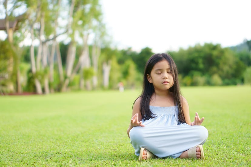 A child meditating in a field. Four letter girl names can have spiritual meanings.