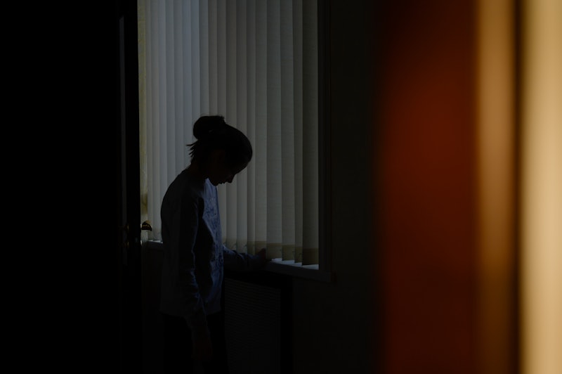 Stock image of a female figure sitting in a darkened room
