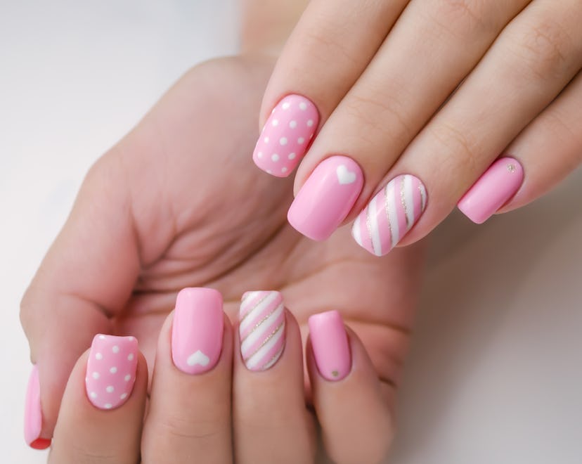 The hand of a young woman. The nails are covered with pink gel polish for Valentine's Day. Nail art ...