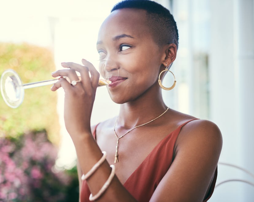 Woman sipping champagne outdoors, in a story answering the question can you drink champagne while br...