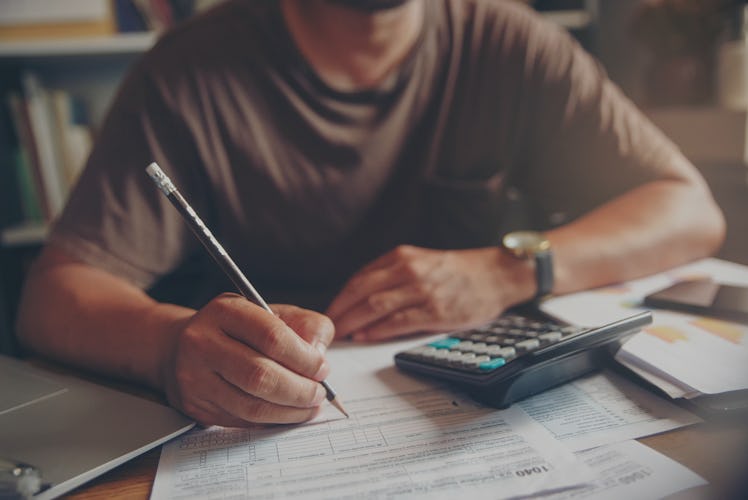 An accountant working at a desk with paper, pencil, and a calculator.