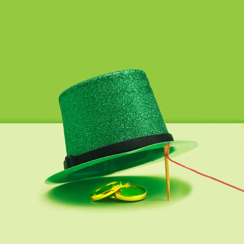 St Patrick minimal treasure concept. Striking green glittery top hat and golden coins under. Vivid g...