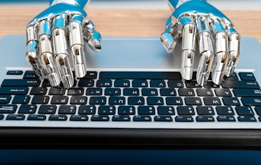 Robot hand typing on laptop.