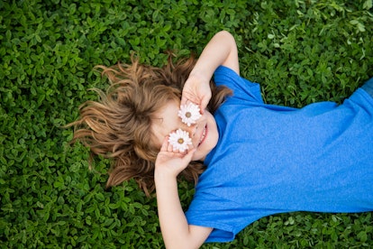 A child lying on the grace with flowers over their eyes. Many unique baby names can be inspired by n...