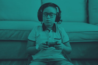 Young kid playing video games, holding a controller and wearing headphones while hiccupping.