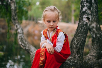 Little girl with white hair in a red, Slavic sundress. 