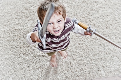 A child holding two swords, looking up at the camera.