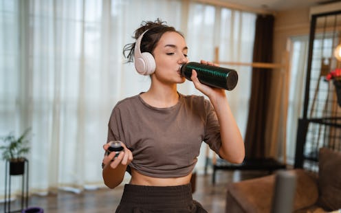 One woman young caucasian female training at home with headphones on Indoor Cycling stationary Exerc...