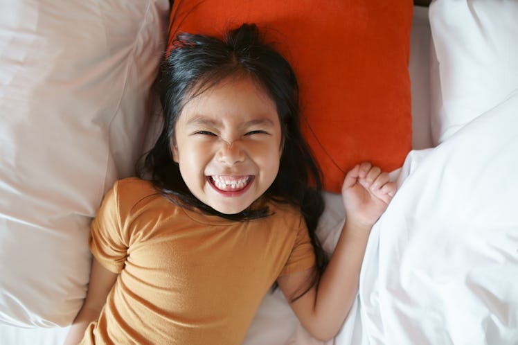 A child in bed smiling with a missing tooth.