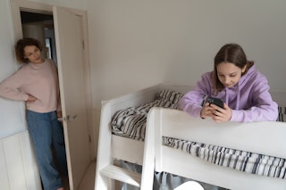 a mom looks in on a teen using a phone. A new TikTok trend has kids sharing if they are their parent...