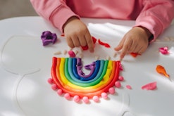 Child hands creating rainbow from play dough for modeling. Art Activity for Kids. Fine motor skills....
