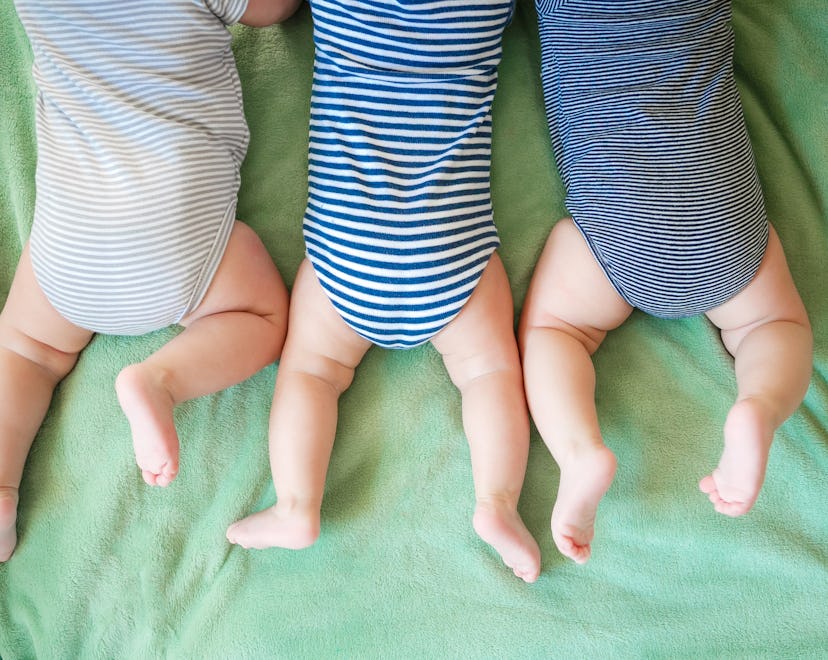 Newborn triplets lie on a stomach on the blanket in an article about triplet boy names