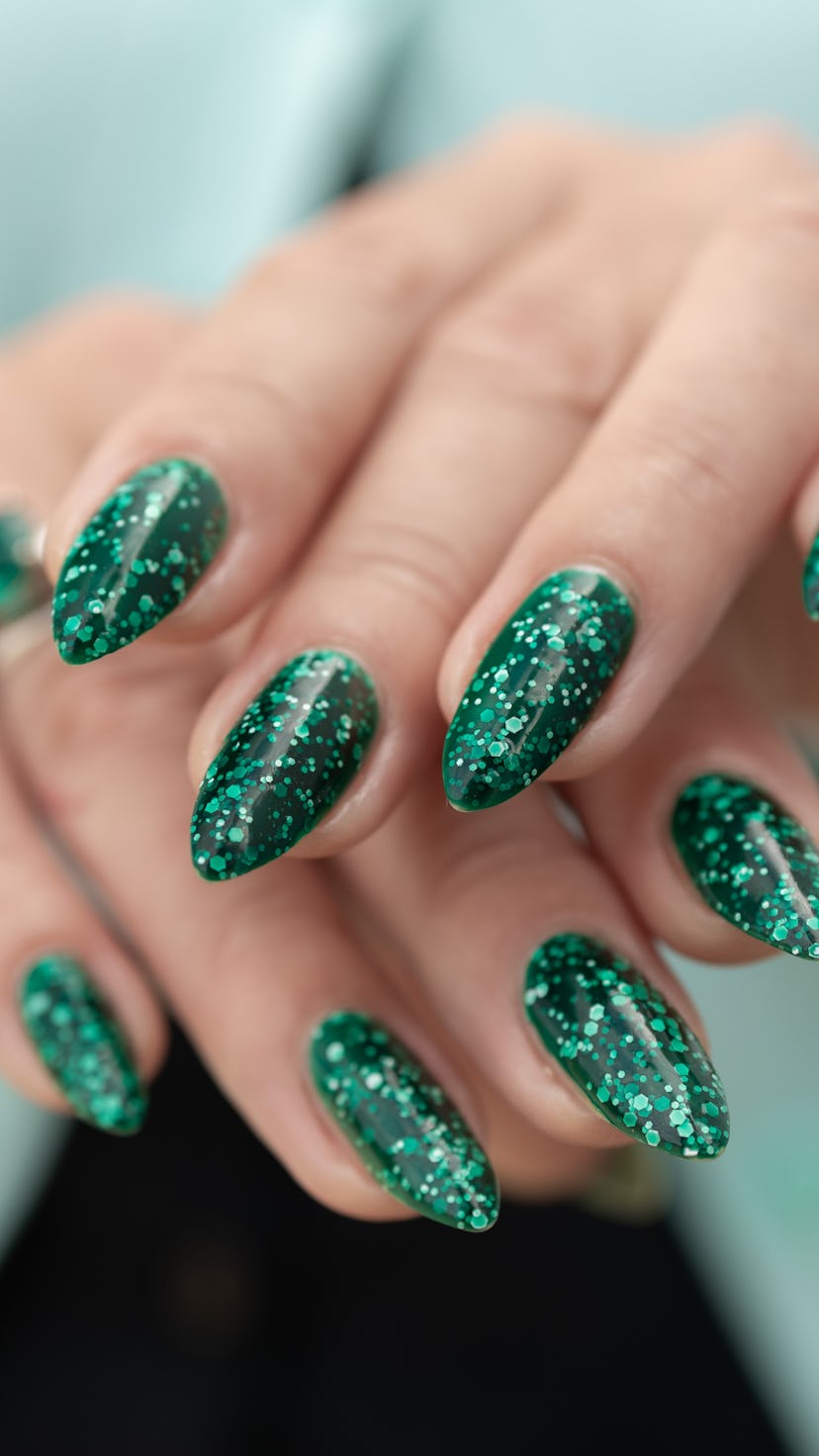 Woman's hand with long nails and green manicure with bottles of nail polish