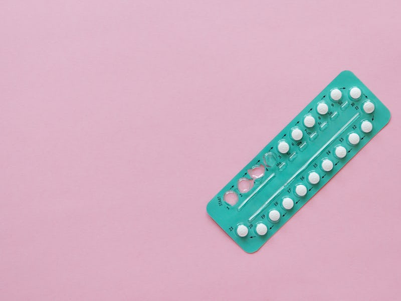 hormonal oral contraceptives in a blister for a month of reception lie on a table on a pink backgrou...