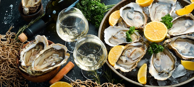 Bottle of aged wine and fresh oysters on a dark kitchen table. Seafood. Top view. Flat lay.